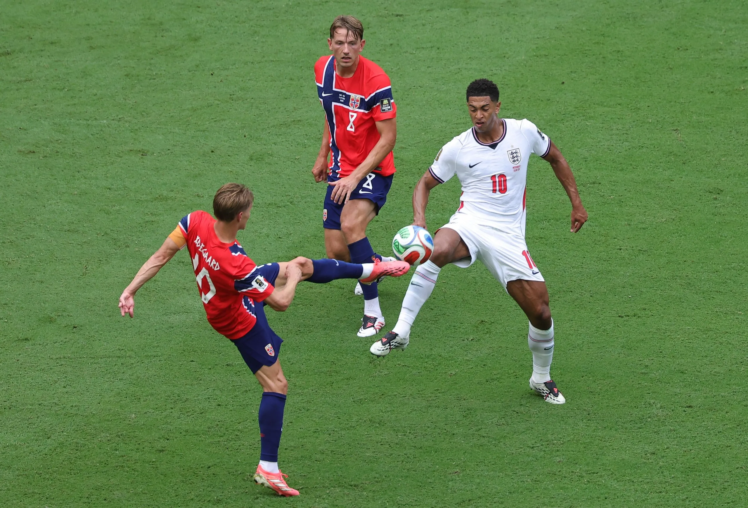 Jude Bellingham jousts for the ball with Martin Ødegaard as Sander Berge watches.
